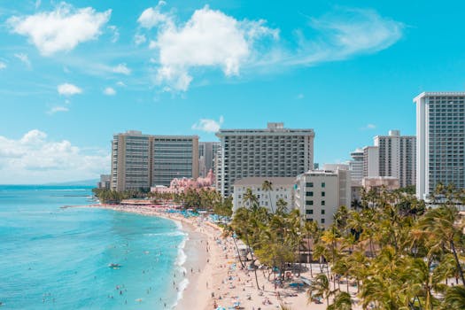 A vibrant aerial view of Waikiki Beach with luxurious hotels and sunlit turquoise ocean.